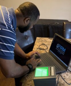 A person working on a laptop and a fingerprint device